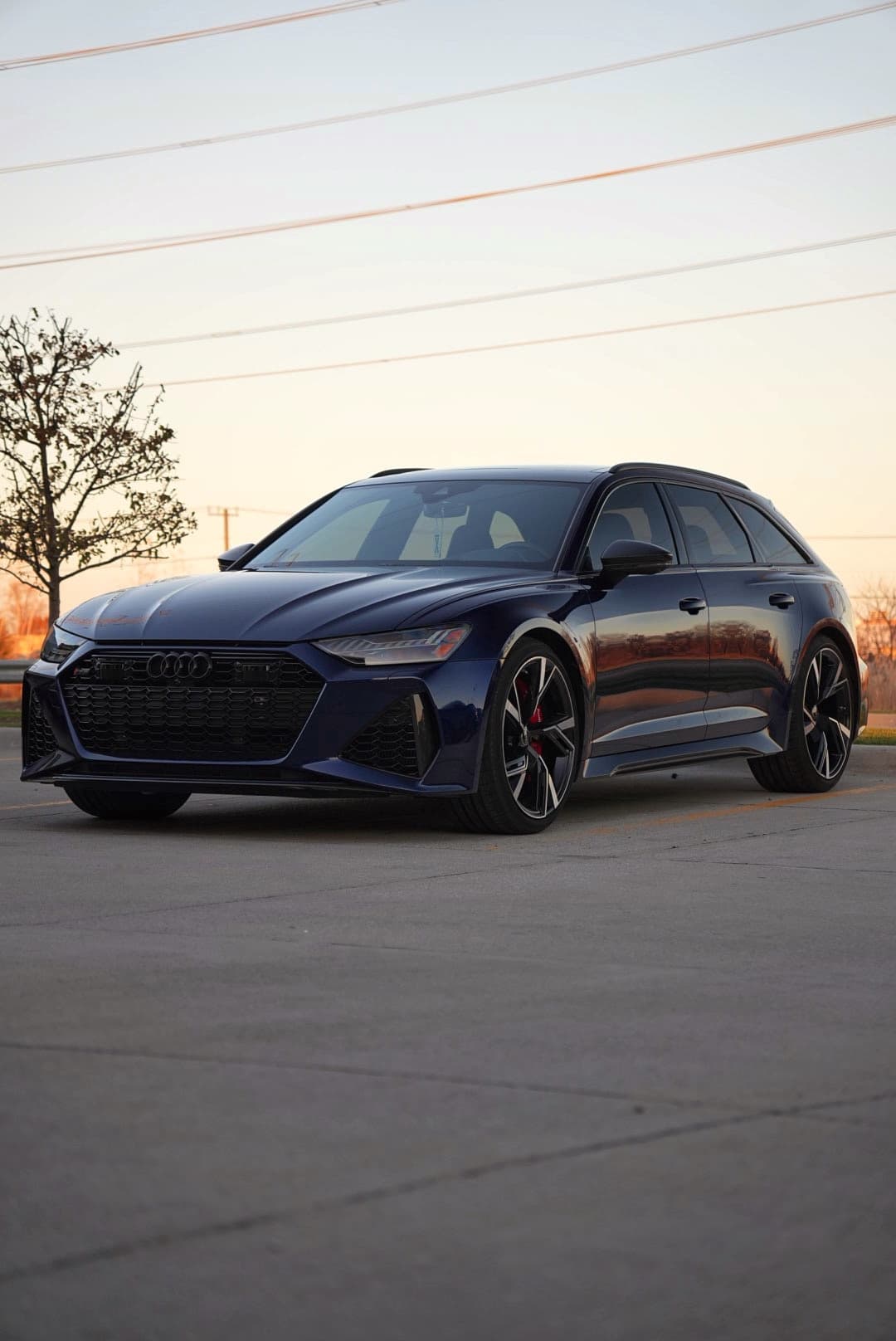 Dark blue Audi RS6 Avant, front three-quarter, at sunset