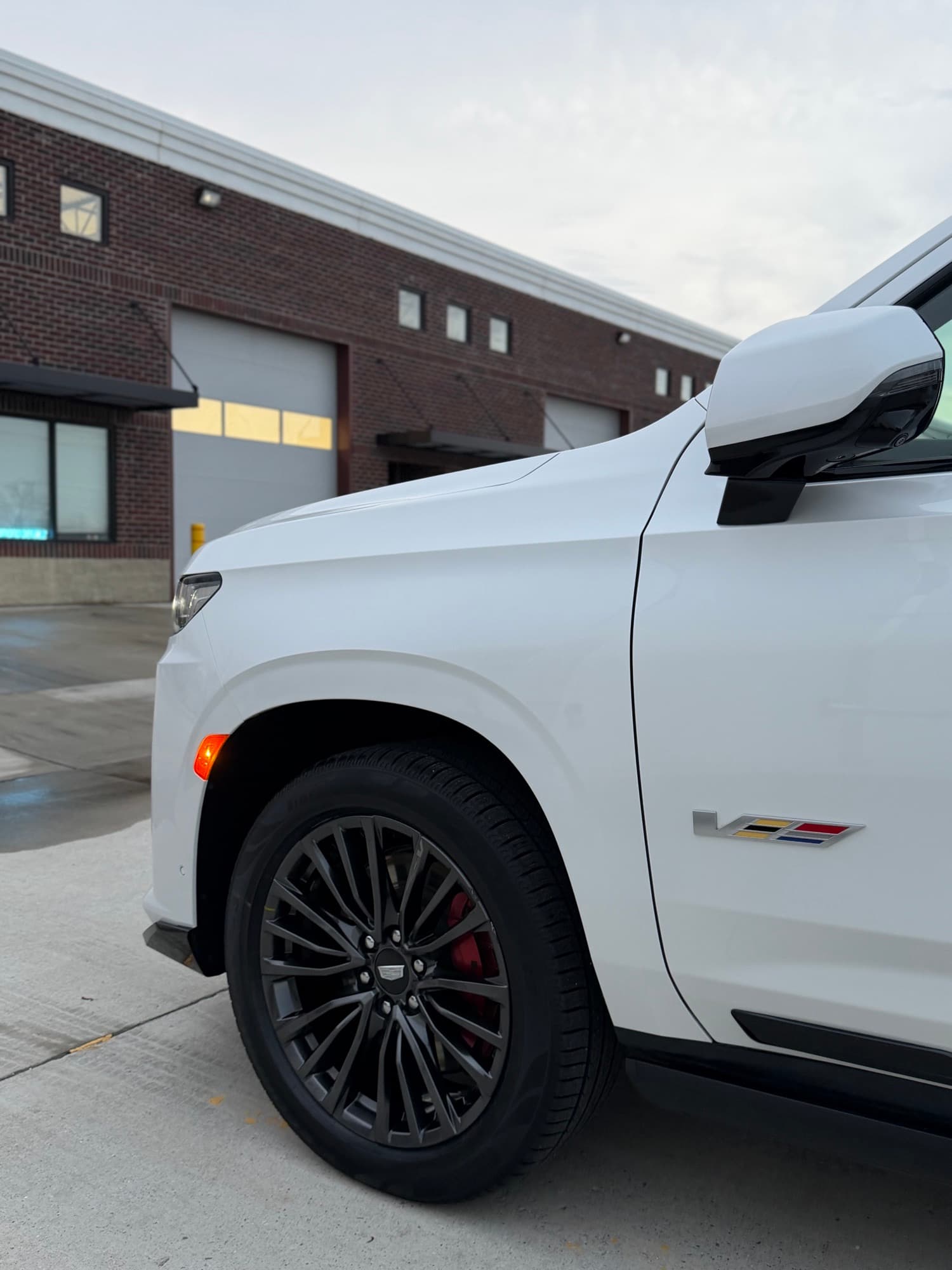 White Cadillac Escalade-V front fender and mirror outside the Diamond Detailz building